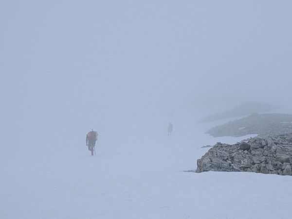 Bergsteiger bewegen sich bei dichtem Whiteout über einen verschneiten Gletscher